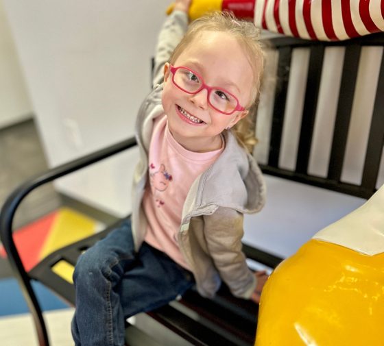 2019_tincher family Girl sitting on bench smiling.